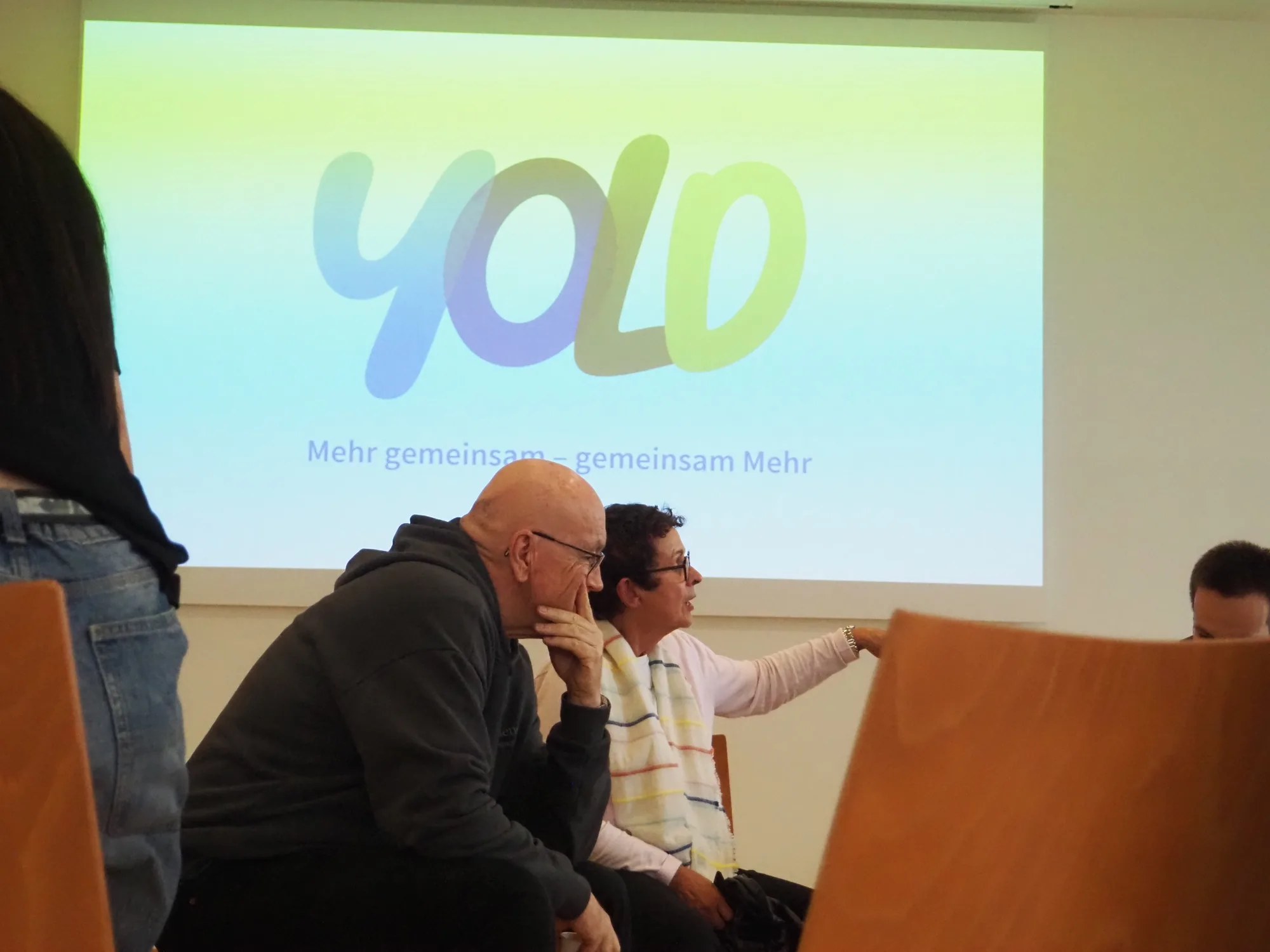 Teilnehmende einer YOLD-Veranstaltung vor dem projizierten YOLD-Logo